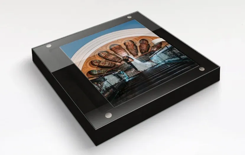 A wedding album with a photograph from the day as its cover, shown inside its presentation box beneath a perspex lid