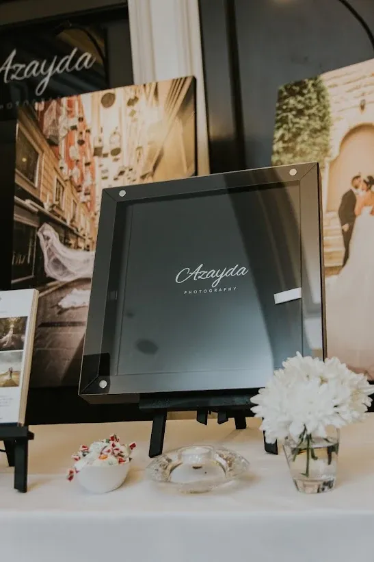 An Azayda wedding album in its black presentation box, displayed alongside framed prints