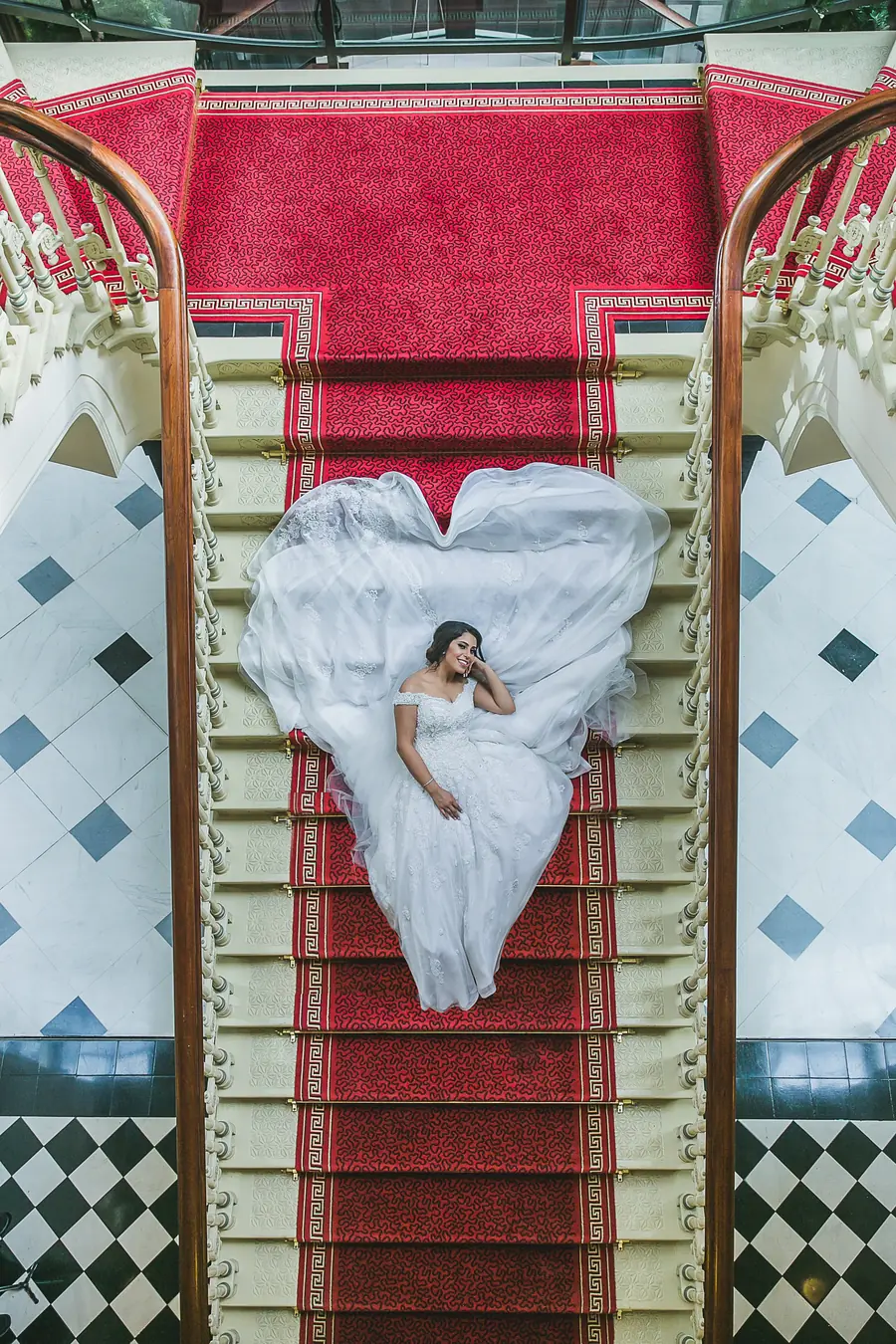 A bride in a white wedding dress on a red-carpeted staircase in Sydney CBD