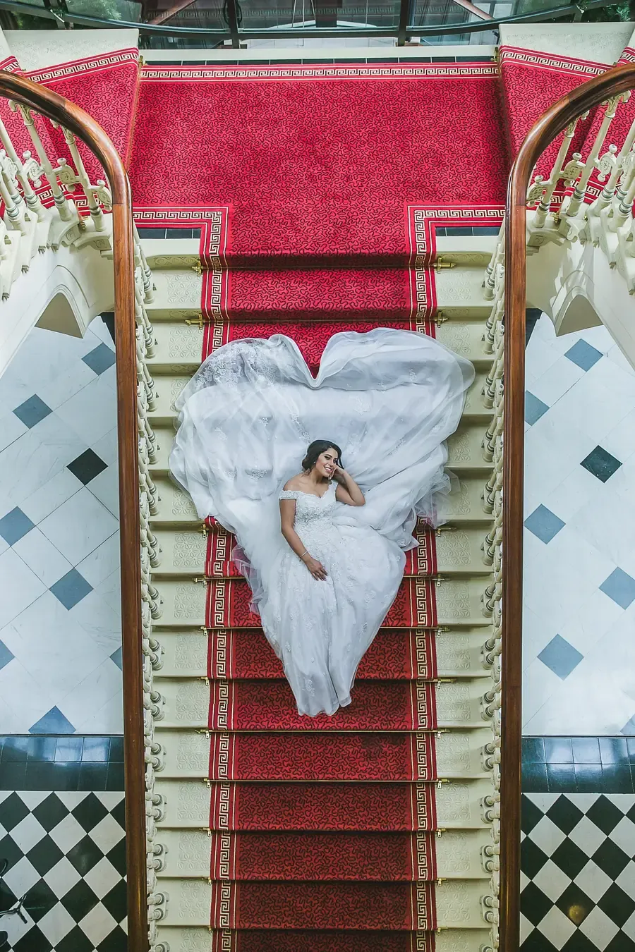 A bride in a white wedding dress on a red-carpeted staircase in Sydney CBD