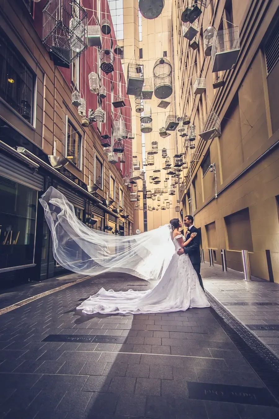 A couple walking beneath hanging birdcages in a Sydney CBD laneway