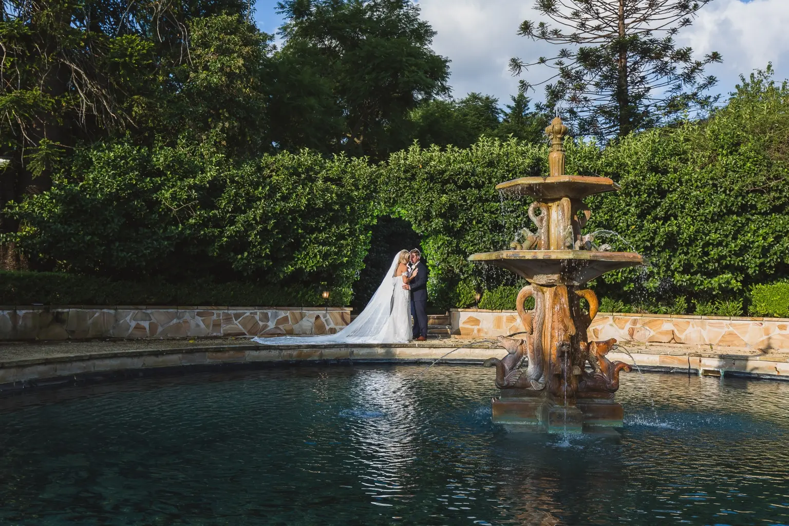 Wedding portrait beside a garden fountain