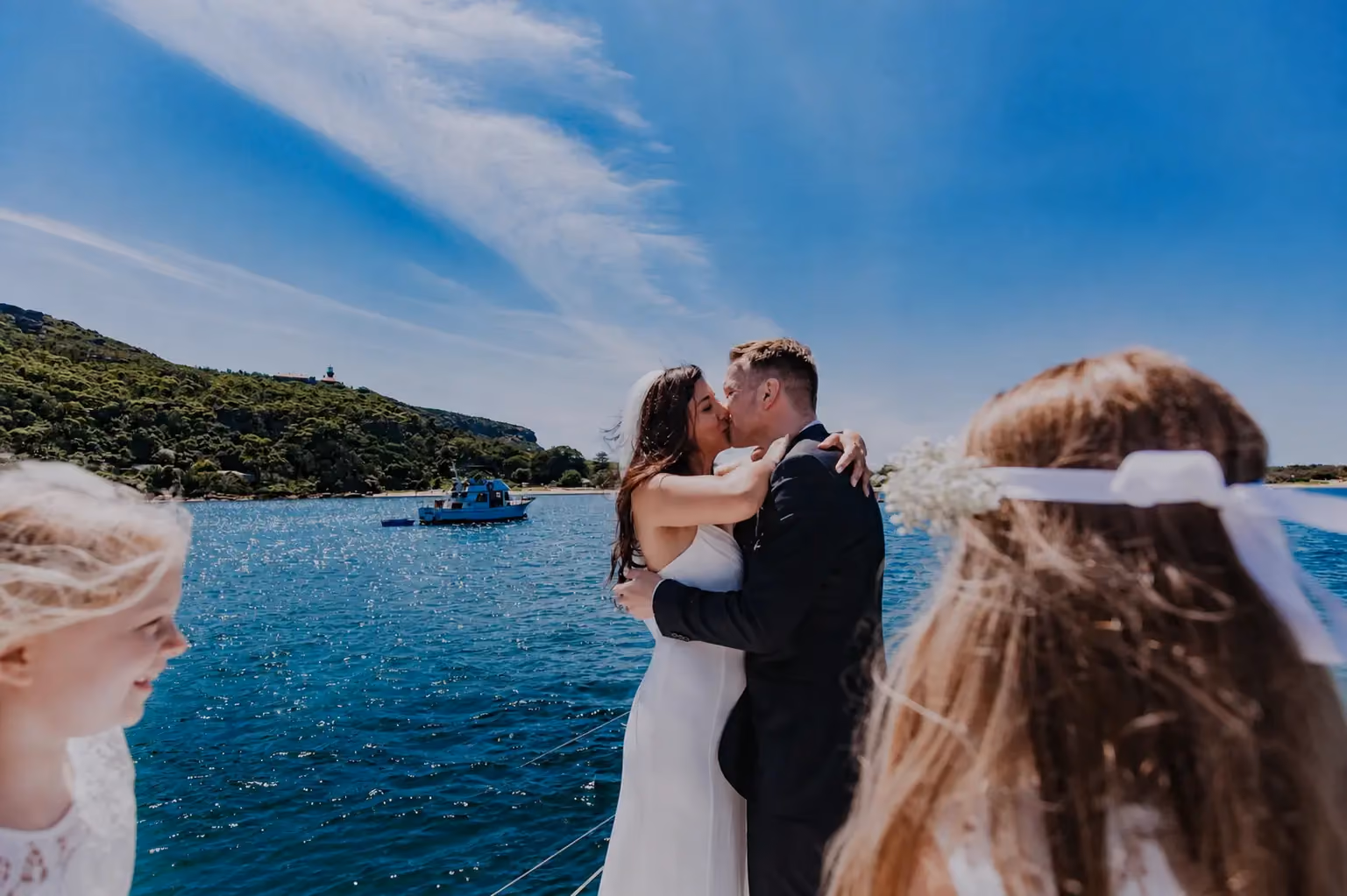 A newlywed couple kissing beneath the QVB arches as petals drift around them