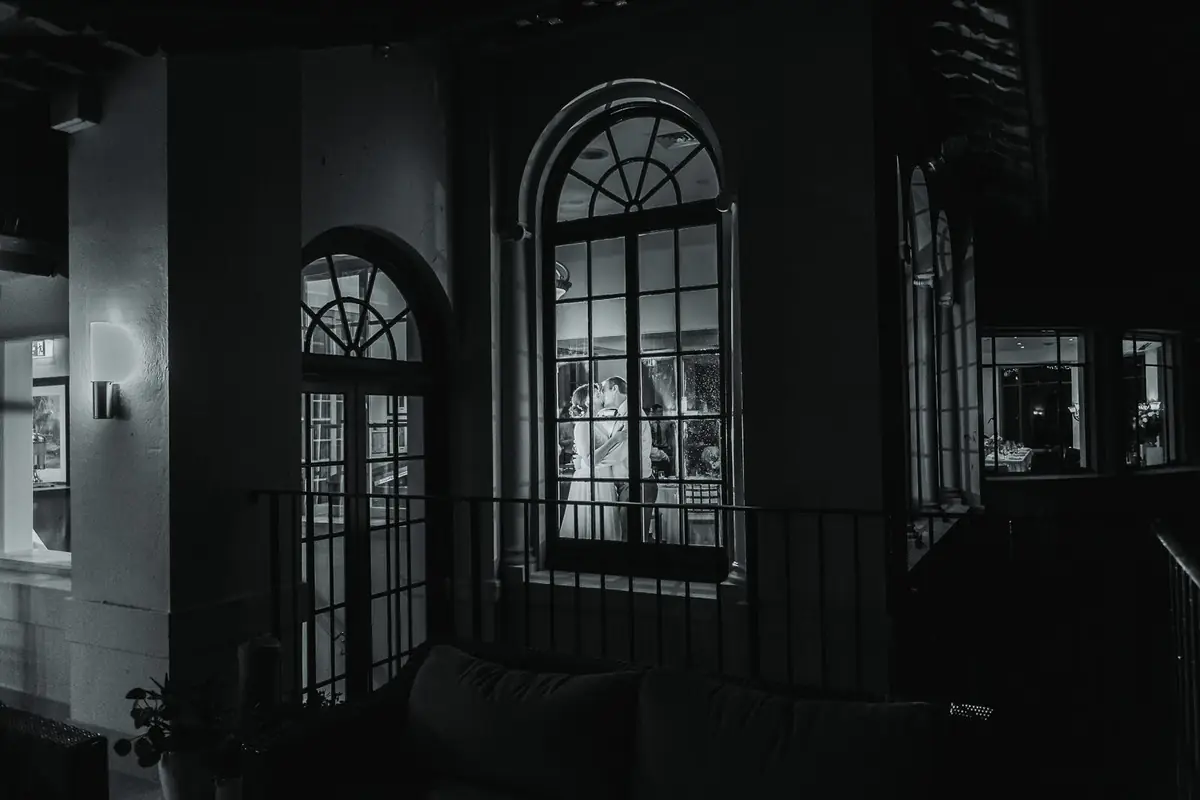 A couple kissing through arched windows at Manly Golf Club in Sydney’s Northern Beaches