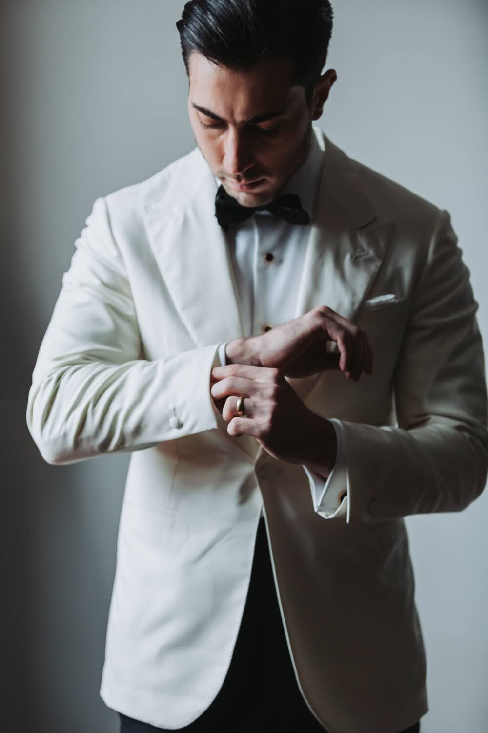 Ivan adjusting his cuff in a white dinner jacket